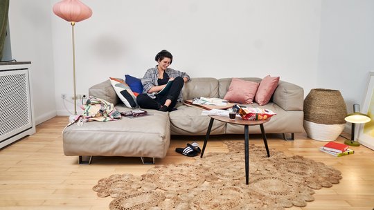 Eine junge hippe Frau hört Musik auf einem Sofa.