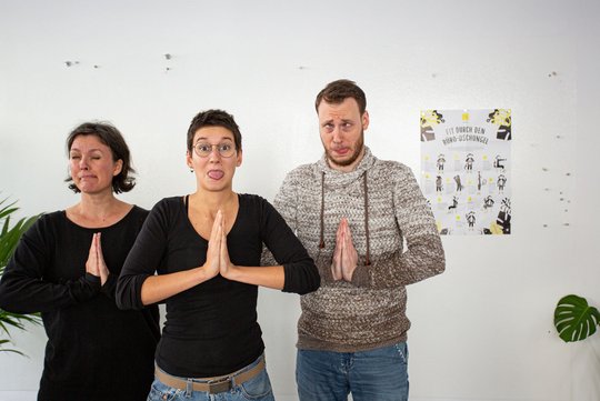 Bernadette, Tiffy und Matt machen eine Rückenübung mit Grimassen