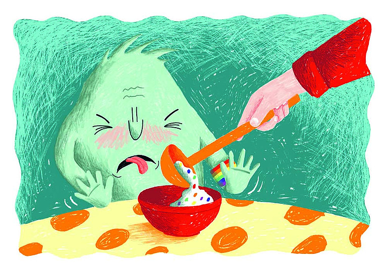 Merti Mutig sitzt am Tisch vor einer Schüssel, in die gerade eine bunte Suppe geschüttet wird. Merti streckt angewidert die Zunge heraus.