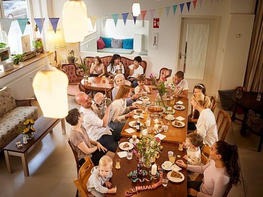 Eine Gruppe aus Freunden mit Kindern sitzt in ANNA am Tisch und feiert.