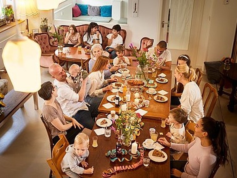 Eine Gruppe aus Freunden mit Kindern sitzt in ANNA am Tisch und feiert.