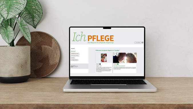 Schreibtisch mit geöffnetem Laptop und dem digitalen Pflegemagazin