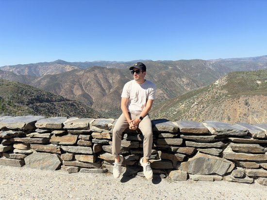 Person sitzt auf einer Steinmauer, im Hintergrund der Yosemite