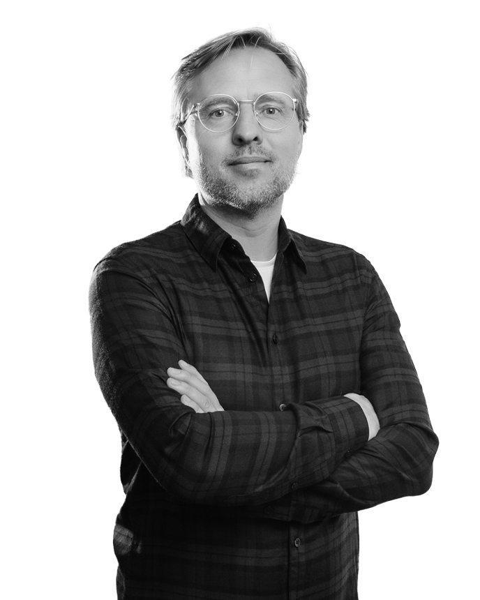 Mann mit Brille, verschränkte Arme, trägt kariertes Hemd.