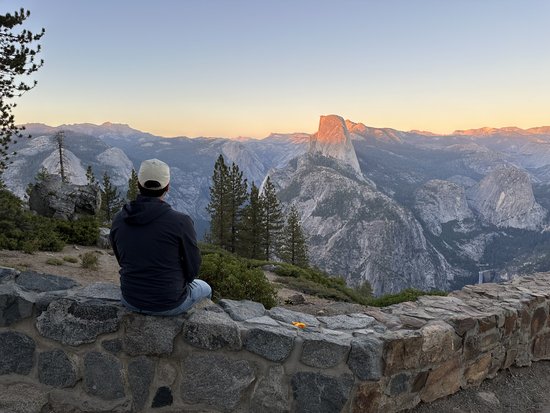 Person sitzt vor einer Skyline mit Bergen und Sonnenuntergang