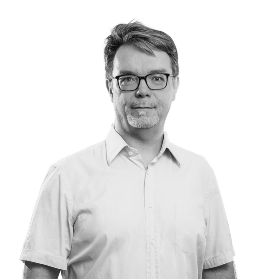 Mann mit Brille in hellblauem Hemd und Jeans vor weißem Hintergrund.