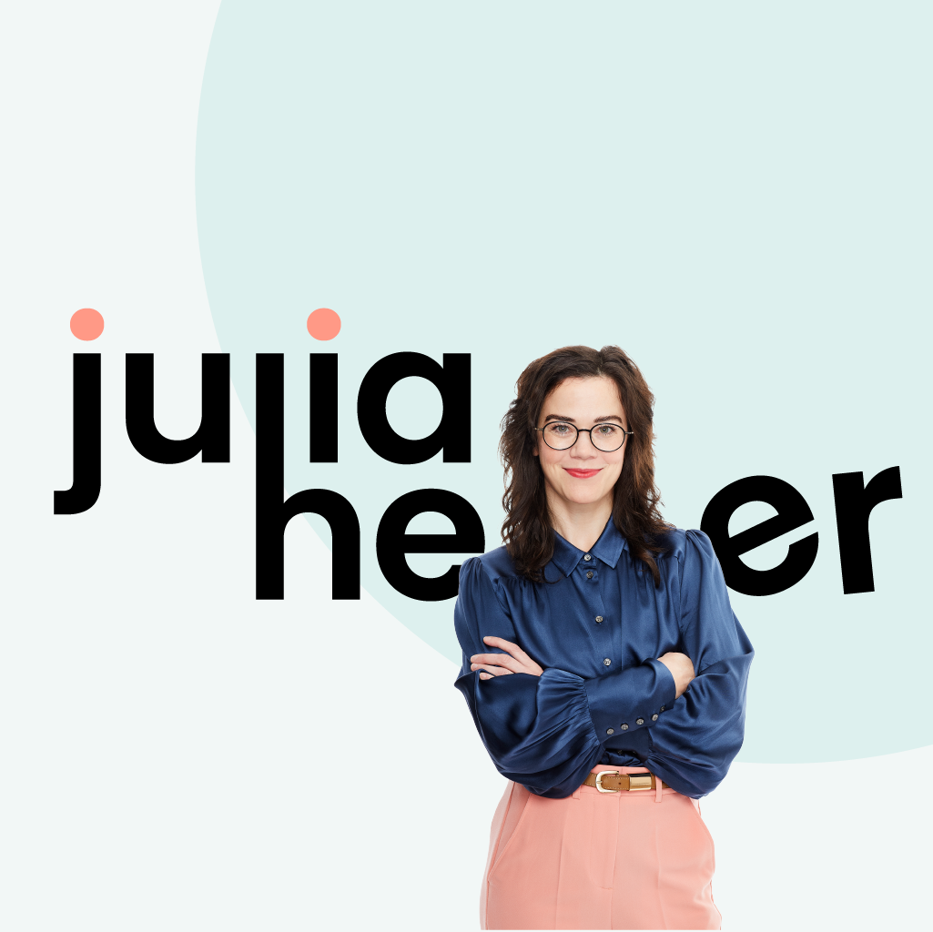 Frau mit Brille und blauer Bluse, Schriftzug "julia heer" im Hintergrund.