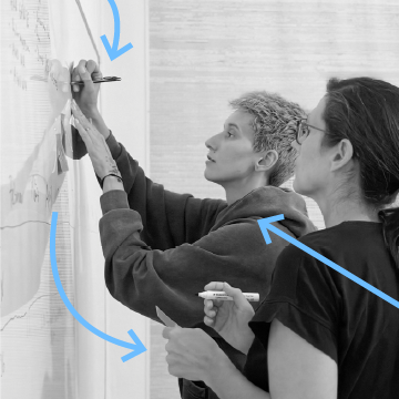 Zwei Personen zeichnen und notieren an einem Whiteboard.